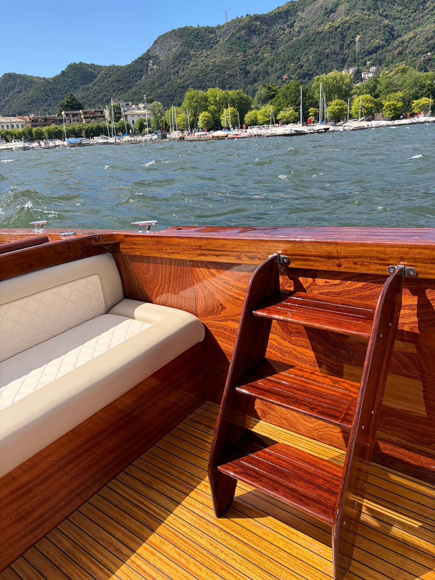 Banquette en cuir ivoire et échelle en acajou à bord, rive de Côme en arrière-plan